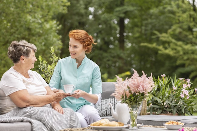 happy-nurse-giving-tea-to-elderly-woman-while-eati-2021-08-26-15-45-19-utc (1)